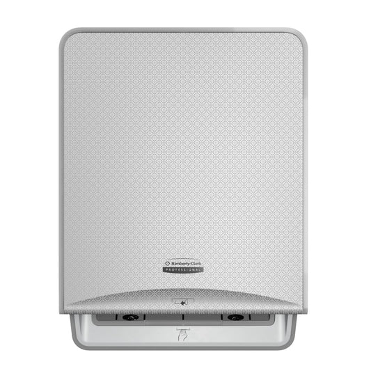 Eine silberne Mosaik, wandmontierte Kimberly-Clark Professional™ Icon™ elektronische No Touch-Losse Modul-Rolle von Kimberly-Clark GmbH mit einer gemusterten Frontplatte, zentralem Logo und einem Schlitz an der Unterseite für berührungslose Handtuchabgabe.