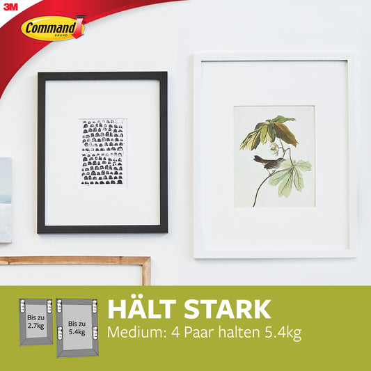 Ein schwarz gerahmter Graustufen-Gesichtsdruck und eine weiß gerahmte botanische Illustration mit einem Vogel auf einem Zweig hängen an einer weißen Wand mit 3M Command Picture Hanging, 10 lb (4,5 kg) Medium White Strips, 17204/PH204, Packung (1 Stück).
