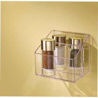 Trois pots à épices en verre avec des couvercles dorés sont placés dans un support transparent, fixé à un mur jaune clair avec le ruban de montage double face transparent Scotch-FIX™ 4910C de 3M Deutschland GmbH. Les pots contiennent des épices brunes, blanches et vertes.