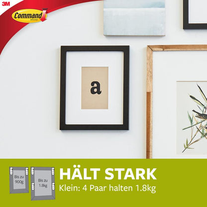 Aan een witte muur zijn meerdere fotolijsten boven een groen spandoek met de tekst "HÄLT STARK" bevestigd, die verwijzen naar de Kleine witte Command™ Bilder-Montage Strips S 17202 van 3M Deutschland GmbH, waarvan vier paar tot 1,8 kg kunnen dragen. In de linker bovenhoek bevindt zich het Command-logo.