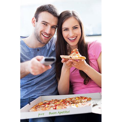 Een man en een vrouw glimlachen op een bank met pizza uit een PAPSTAR 100 pizzadozen, cellulose 'pure' vierkante doos van PAPSTAR GmbH; op de milieuvriendelijke doos van pure cellulose staat 'pure Buon Apetito!', terwijl hij een afstandsbediening vasthoudt.