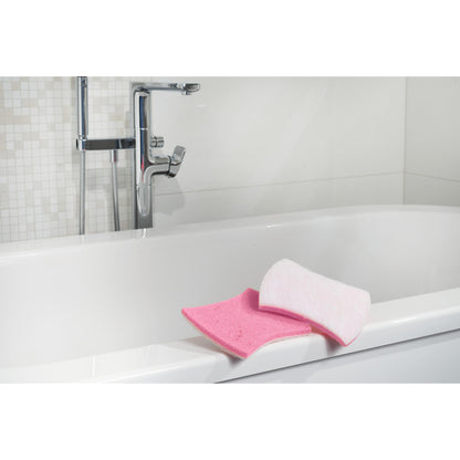 Gezeigt wird eine weiße Badewanne mit verchromten Armaturen. Am Rand befinden sich ein rosa Badezimmerschwamm und ein Scotch-Brite® Bath XXL Reinigungsschwamm für das Bad von 3M Deutschland GmbH. Der Hintergrund zeigt weiße Fliesen mit Mosaikmuster.
