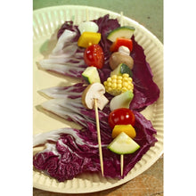Deux PAPSTAR brochettes en bambou "pure" (2,5 mm x 20 cm) de PAPSTAR GmbH, garnies de tomates cerises, champignons, maïs, courgettes, poivrons et oignons, reposent sur une assiette en carton garnie de feuilles de radicchio violettes.