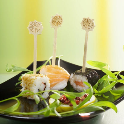 Drie sushi-stukken op een zwart bord, elk uniek belegd en vastgezet met de PAPSTAR Fingerfood-picker "Stuurwiel" 9 cm van PAPSTAR GmbH, zijn perfect voor feestjes. Groene garnering en rode saus versieren het gerecht en bieden een stijlvolle catering met de kartonnen tray (200 stuks).