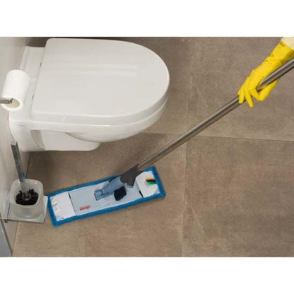 Een persoon met gele handschoenen veegt efficiënt de betegelde badkamer vloer naast een witte toilet met de Vileda Professional SprayPro roestvrijstalen mopphouder van Vileda GmbH, die is uitgerust met een pad met blauwe rand. In de buurt bevindt zich een houder waarin de toiletborstel wordt bewaard.