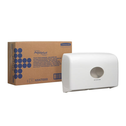 Un distributeur double rouleau Aquarius™ blanc pour papier toilette Jumbo Mini de Kimberly-Clark GmbH est fixé au mur à côté d'une boîte brune avec l'inscription "Aquarius" et un graphique à points bleus ainsi que des informations sur le produit.