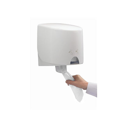 Een hand trekt een WypAll® L10 papieren doekje voor voedsel & hygiëne uit een witte, aan de muur gemonteerde dispenser van Kimberly-Clark GmbH met centrale afname voor een effen achtergrond.