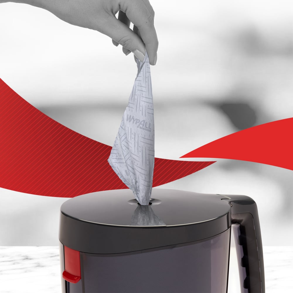 Eine Hand zieht ein WypAll® Reach™ Papierwischtuch für Lebensmittel & Hygiene - Zentralentnahme von Kimberly-Clark GmbH aus einer grauen Dose, die Hygiene fördert. Im Hintergrund sind rote, geschwungene Linien zu sehen.