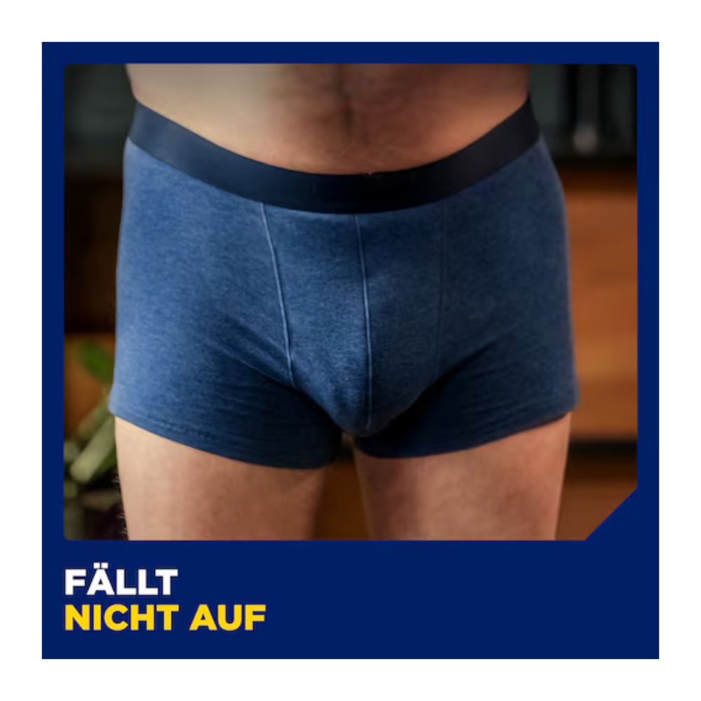 Ein Mann trägt blaue Unterwäsche zur Demonstration von Muster TENA Men Active Fit von TENA - Essity Germany GmbH, die von der Taille bis zur Mitte des Oberschenkels vor einem unscharfen Hintergrund gezeigt wird. Auf einem blauen Banner darunter steht in weißen und gelben Buchstaben "FÄLLT NICHT AUF".