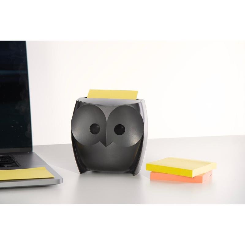 Een 3M Post-it® Z-Notes Dispenser in uilenvorm, zwart, houdt gele Super Sticky Z-Notes vast. Daarnaast liggen een gesloten laptop en een pak met gele en roze Z-Notes (2 blokken à 45 vel) op een wit bureau.