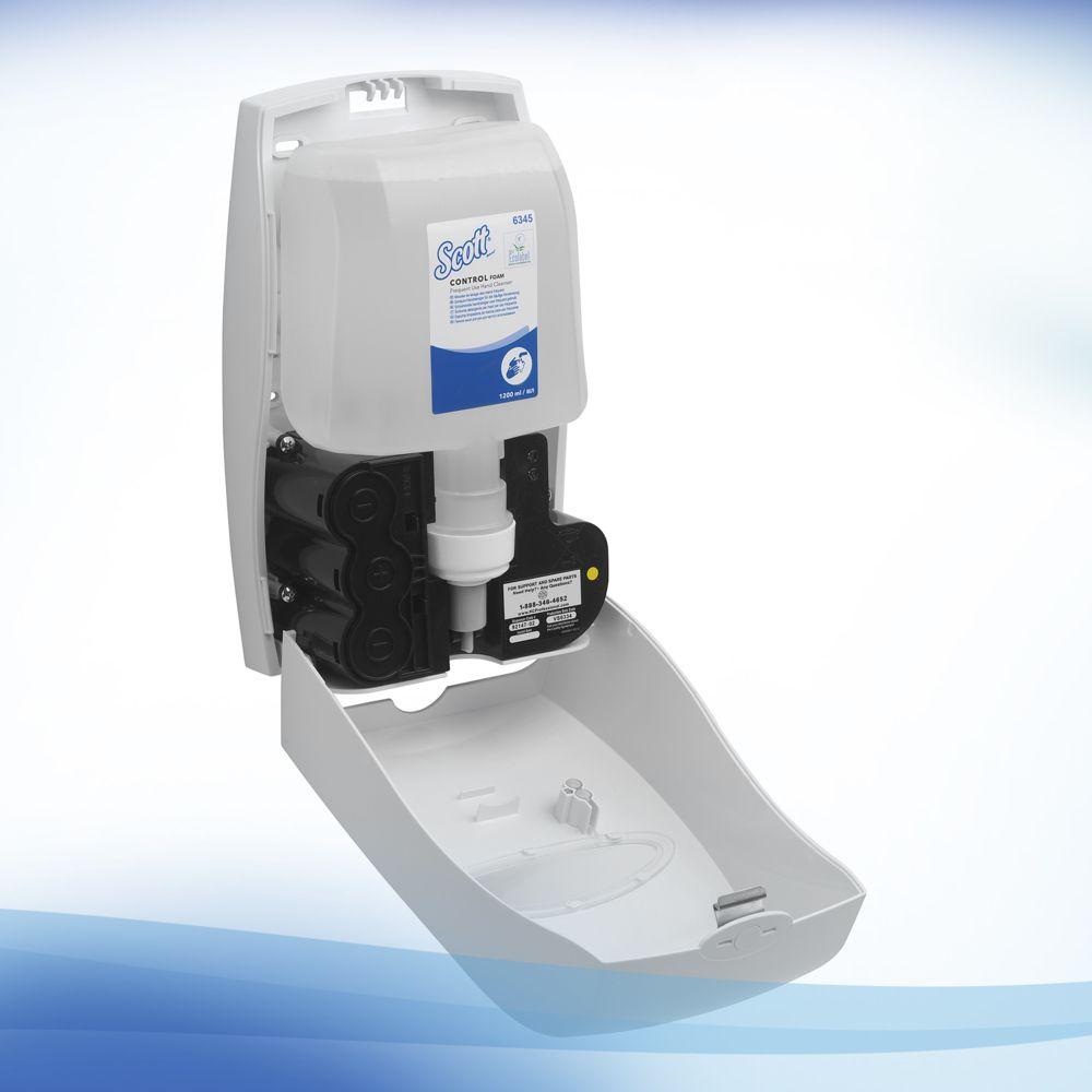 Een aan de muur gemonteerde zeepdispenser met geopende voorkant toont een Scott® Control™ Schuim-handreiniger navulling van Kimberly-Clark GmbH. Hij is afgebeeld tegen een wit-blauwe achtergrond met kleurverloop en is ideaal voor handhygiëneprotocollen. De doos bevat 4 patronen.