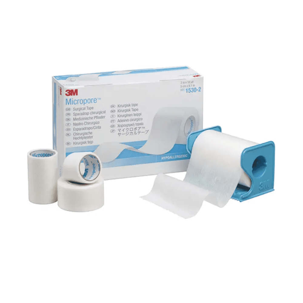 De afbeelding toont een 3M Healthcare Germany GmbH 3M-Medica Micropore pleister, huidskleur - 12 stuks | Verpakking (12 stuks)-doos met pleisters in verschillende maten ervoor. Een pleisterrol bevindt zich in een blauwe dispenser, terwijl twee andere pleisterrollen en een kleinere rol rechtop naast de doos staan. De hypoallergene pleister is wit.