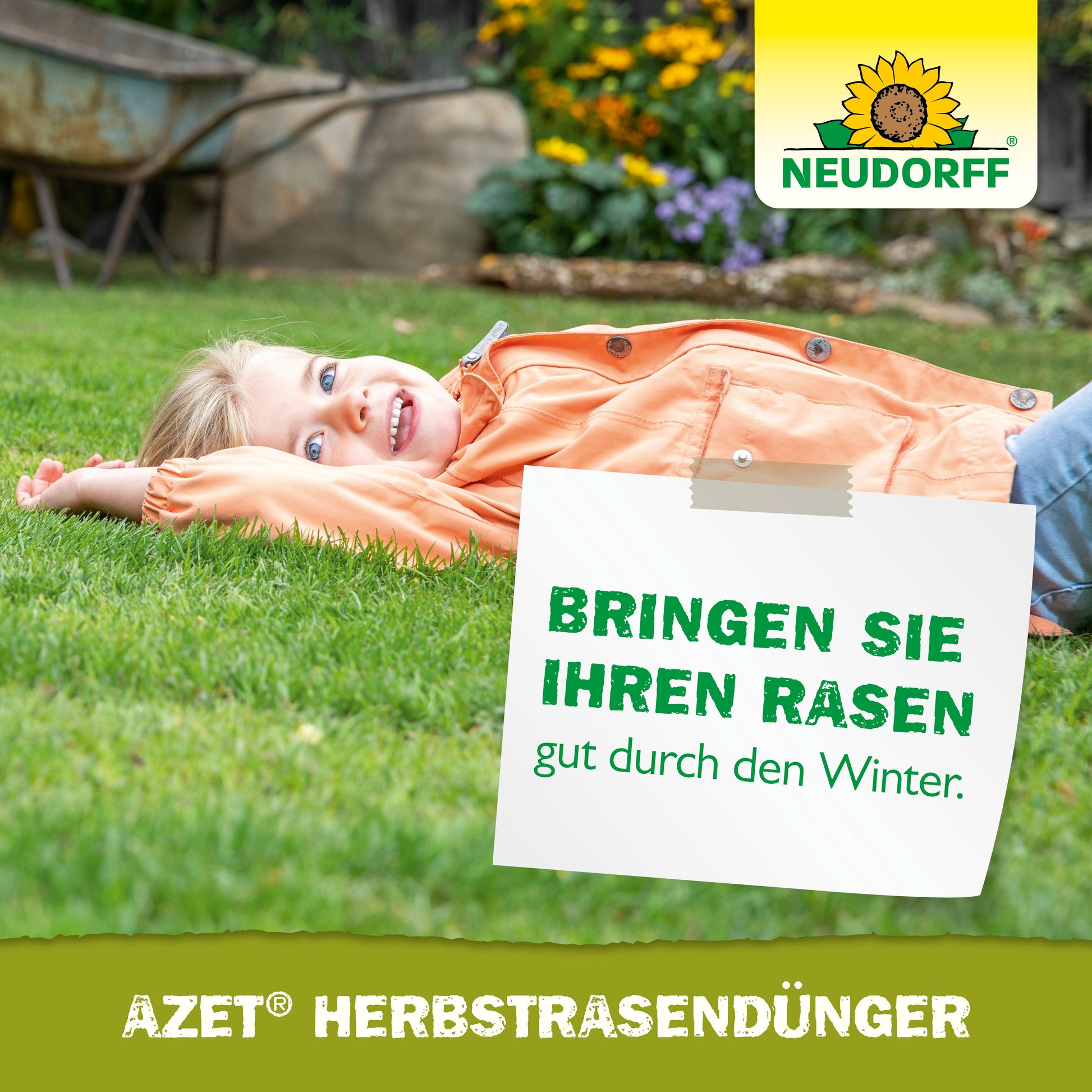 Ein Kind in einer orangefarbenen Jacke lächelt auf grünem Gras. Auf einem deutschen Schild steht: "Bringen Sie Ihren Rasen gut durch den Winter." Der Azet HerbstRasenDünger aus dem Neudorff Shop, ein organischer Rasendünger, ist gut sichtbar gebrandet.