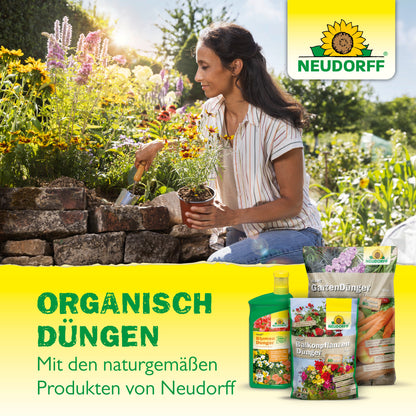 Eine Frau pflanzt Blumen in einem Hochbeet - ideal für Balkonpflanzen. Der Azet Buxus- & IlexDünger flüssig von Neudorff Shop ist ausgestellt, mit einem Text, der für regelmäßige Düngergabe mit Neudorff Shop wirbt.