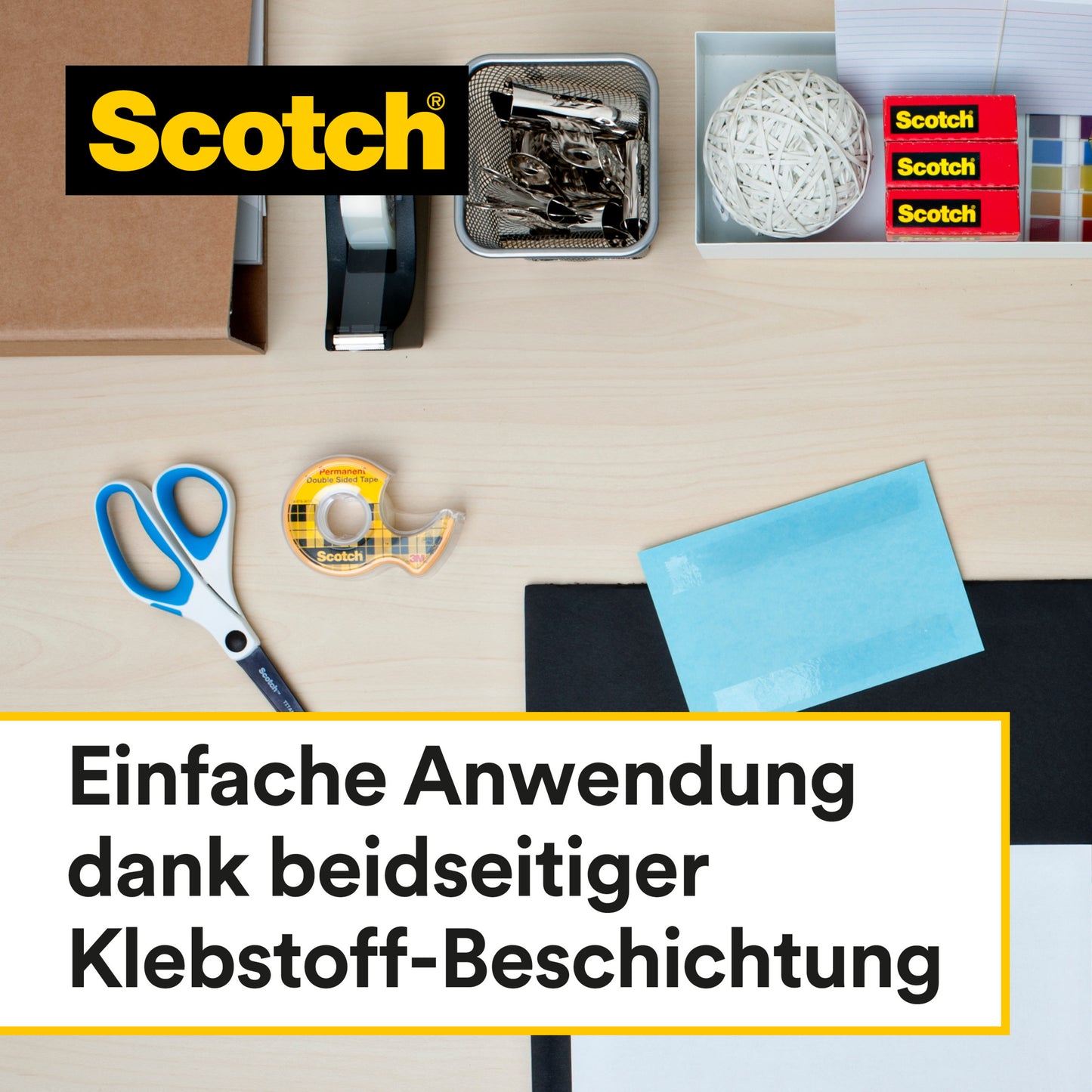Ein Schreibtisch mit Bürobedarf, darunter Scotch® doppelseitiges Klebeband 12,7 mm x 7,89 m mit Handabroller von 3M Deutschland GmbH, Schere, Heftgerät, Büroklammern, Gummiball, Haftnotizen und Briefumschläge. Text: Einfache Anwendung dank beidseitiger Klebkraft.