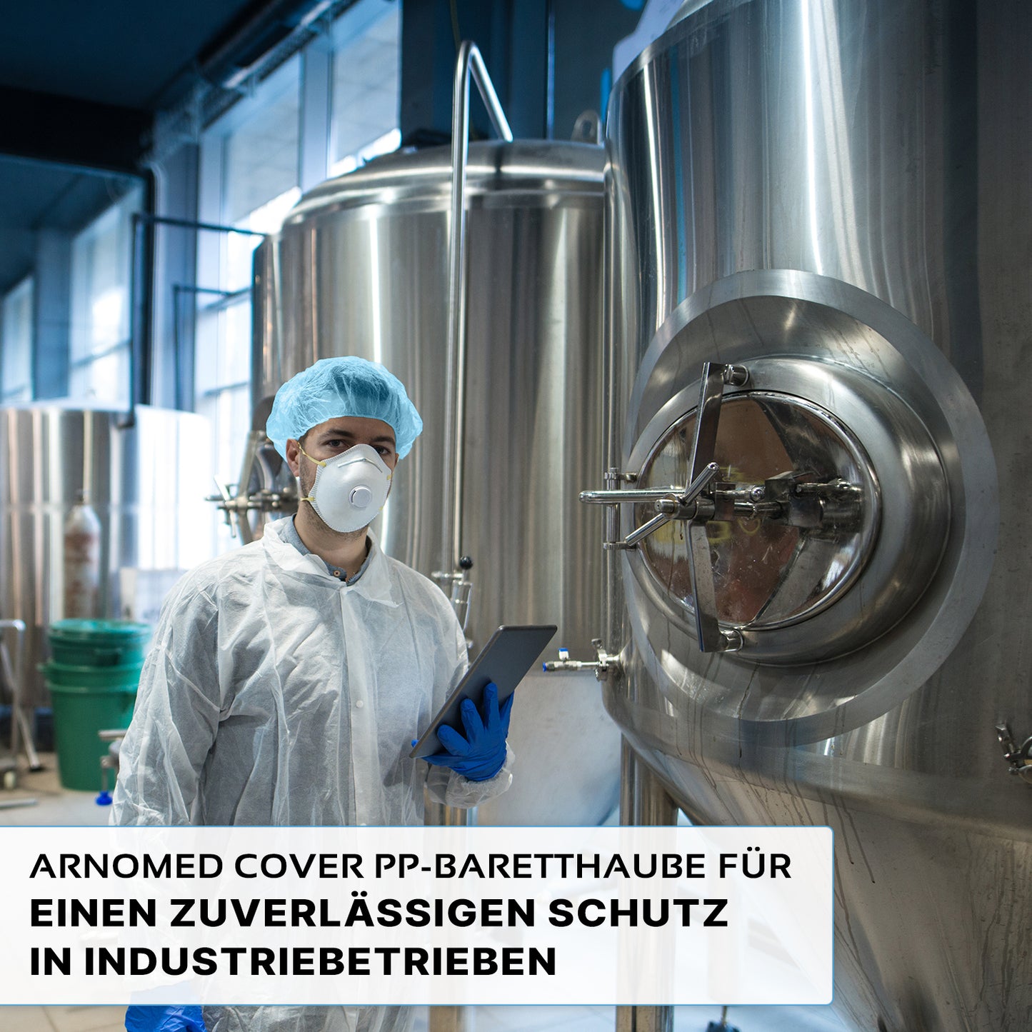 Een persoon die een ARNOMED COVER PP-BARETTHAUBE baretkap van PP-vlies van ARNOWA GmbH en een masker draagt, staat voor roestvrijstalen tanks in een industriële hygiënezone en houdt een tablet in de hand. De Duitse tekst benadrukt de betrouwbare bescherming voor de industrie.
