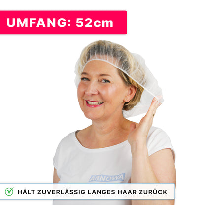 Glimlachende vrouw draagt ARNOMED COVER PP-BARETTHAUBE van PP-vlies van ARNOWA GmbH en houdt een zijde vast. Roze vlag: "OMTREK: 52cm." Tekst: "Houdt betrouwbaar lang haar terug - ideaal voor de hygiënezone."