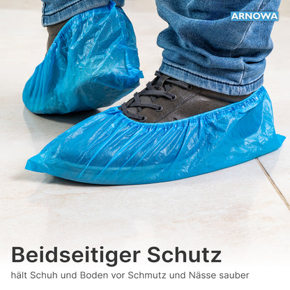 Eine Person trägt ARNOMED CPE Schuhüberzieher von ARNOWA GmbH über dunklen Schuhen auf hellen Fliesen. Am Bildrand wird für den Schutz von Schuhen und Böden vor Schmutz und Feuchtigkeit geworben. Beutel mit 100 Stück, wasserdicht, Einweg.