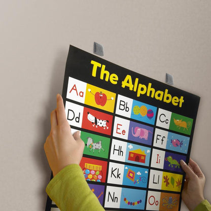 Une personne montre un tableau alphabétique vivant avec des lettres illustrées, temporairement fixé sur un mur lisse avec les carrés de montage amovibles Scotch-FIX™ 108-ST64-P, 12,7 mm x 12,7 mm, de 3M Deutschland GmbH, et facilement amovible. Le paquet contient 64 pièces.