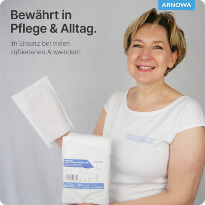 Une femme en chemise blanche avec le logo Arnova tient un paquet blanc et un gant de toilette jetable ARNOMED en molleton (75g/m², 50 pièces, Dermatest) de ARNOWA GmbH. Au-dessus d'elle se trouve un texte en allemand: "Éprouvé dans les soins & au quotidien. Utilisé par de nombreux utilisateurs satisfaits."