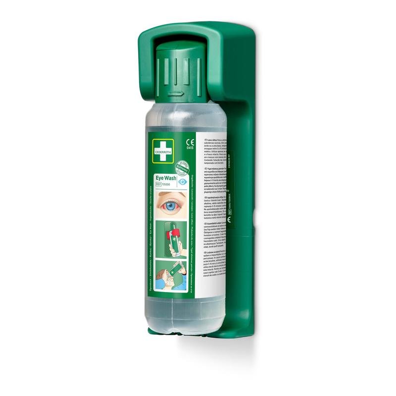 Een groene Orkla Wound Care AB wandhouder bevat een 500 ml oogspoelfles met groene dop, de opdruk "Eye Wash" en een gebruiksaanwijzing; inclusief een in het donker oplichtend bord. De verpakking bevat 1 wandhouder voor nood-oogspoelstations.
