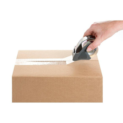 Une main ferme un carton brun sur la couture supérieure avec du ruban d'emballage Scotch® Box Lock™ 48 mm x 20,3 m de 3M Deutschland GmbH avec un dévidoir de ruban adhésif, le tout sur un fond blanc.