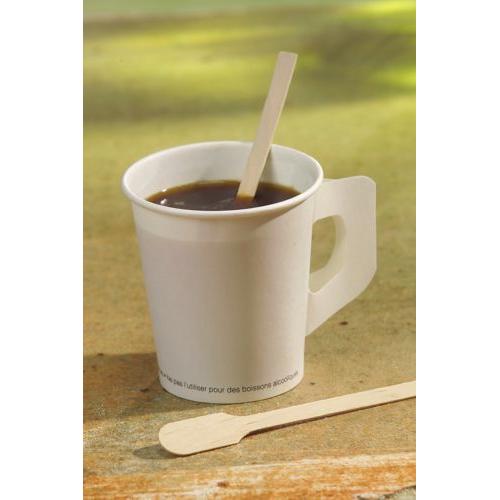 Un gobelet jetable blanc avec du café noir tient un PAPSTAR bâtonnet en bois "pure" (13 cm), à côté un autre bâtonnet en bois écologique de la PAPSTAR GmbH. L'arrière-plan est légèrement flou.