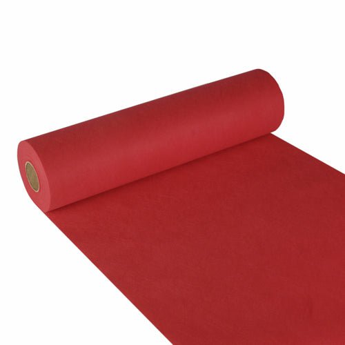 Een rol Starpak tafelloper, stofachtig vlies „Soft Selection“ (24 m x 40 cm), is gedeeltelijk uitgerold op een witte ondergrond, de rol ligt links en de rode loper reikt tot aan de onderste rechterhoek.