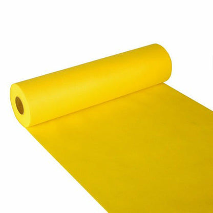 Een rol Starpak tafelloper, stofachtig vlies „Soft Selection“ (24 m x 40 cm), in helder geel, is uitgespreid op een wit oppervlak en toont het zachte papier dat uit de cilindrische Starpak-rol steekt.
