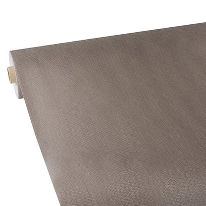 Un rouleau de nappe Starpak, semblable à du tissu, non-tissé "soft selection plus" en brun clair est partiellement déroulé sur une surface blanche, avec à gauche le noyau résistant de cette nappe Starpak visible.