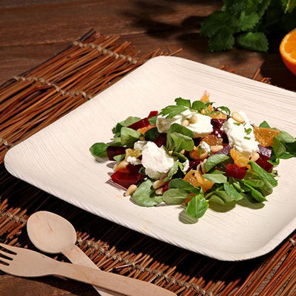 Une élégante assiette PAPSTAR 25, feuille de palmier « pure » de PAPSTAR GmbH, sert une salade fraîche sur un set de table tissé - idéale pour des occasions spéciales avec son design écologique.