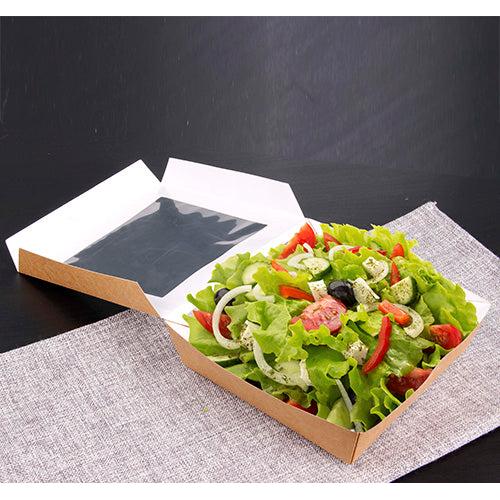 Die PAPSTAR 25 Feinkostboxen aus Pappe mit PLA-Sichtfenster von PAPSTAR GmbH präsentieren frischen Salat mit Dressing auf einer grauen, gewebten Platzmatte auf dunkler Oberfläche – umweltfreundlich verpackt und stilvoll serviert.