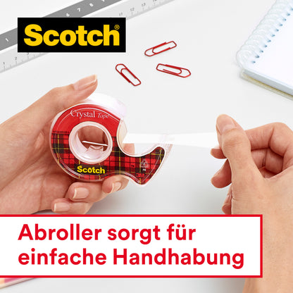 Eine Person benutzt das Scotch® Crystal Klebeband (19 mm x 7,5 m, 1 Rolle + Handabroller) der 3M Deutschland GmbH an einem weißen Schreibtisch mit Büroklammern, einem Lineal und einem Notizbuch. Text auf Deutsch: "Abroller sorgt für einfache Handhabung.