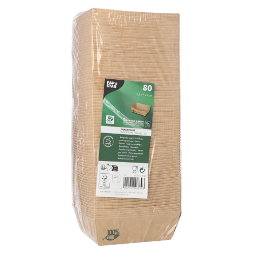 Een verpakte verpakking met 80 PAPSTAR snacktrays "pure" bruin "100% Fair" van de PAPSTAR GmbH staat rechtop, met een etiket op de voorkant dat productdetails en symbolen voor milieuvriendelijkheid en biologisch afbreekbaar toont; de doorzichtige verpakking geeft zicht op gestapelde schalen binnenin.