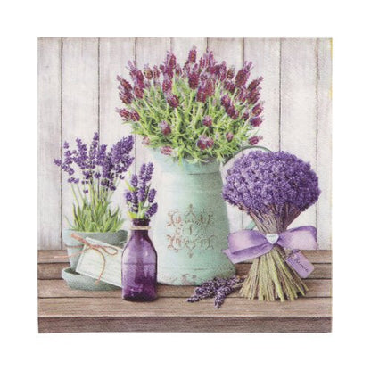 Un bouquet de lavande, une bouteille violette, un pichet blanc avec de la lavande et une tasse de thé verte sont posés sur du bois à côté de PAPSTAR GmbH 20 serviettes 33x33 cm 3 plis 1/4 pliage Design Set 3 devant un mur en bois blanc.