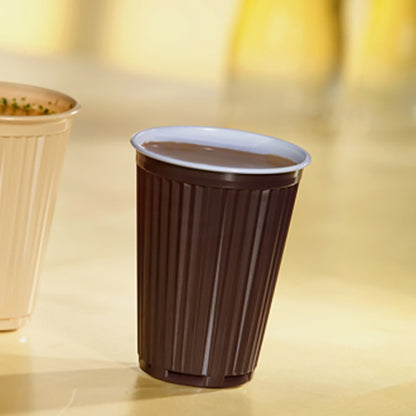 Een met drank gevuld Starpak 100 Thermo-automaatbeker (PS, 0,18l, Ø7,03cm, 9cm, bruin/wit) staat op een lichte plank naast een andere beker; ideaal voor drankjes onderweg. Verpakking met 100 stuks.