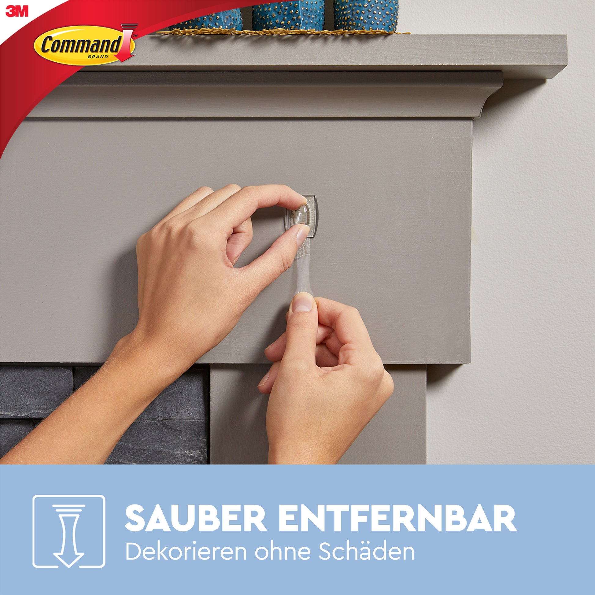 Eine Hand entfernt einen transparenten Command™ Mini-Haken (3M Deutschland GmbH) rückstandsfrei von einem grauen Kaminsims mit Vase. Text: "Sauber entfernbar. Dekorieren ohne Schäden.