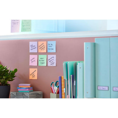 Een roze muur met Post-it® Super Sticky Notes (47,6 x 47,6 mm, 90 vel, 100% PEFC) van 3M Deutschland GmbH, een groene plant, een doos met patroon, een schaar, geordende mappen op het bureau en verdere notities op een glazen plaat erboven.