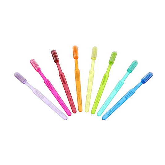 Sieben leuchtende AMPri MED-COMFORT Dental PS Einmal-Zahnbürsten mit Zahnpasta sind ordentlich in einer Reihe angeordnet. Von links nach rechts sind die Farben lila, rosa, rot, orange, gelb, grün und blau. Jede hat ein ähnliches Design mit weichen Borsten, die sich perfekt für die Zahnpflege unterwegs eignen.