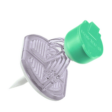 Le B. Braun Mini-Spike® V avec valve de B. Braun Deutschland GmbH & Co. KG est présenté en forme de cœur avec un corps transparent et une pointe verte. Il dispose d'une valve intégrée pour une fonctionnalité supplémentaire et possède une pointe acérée en bas pour fixer des objets sur des surfaces.