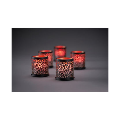 Acht gloeiende Multicolour LED Set, Mini-kaarsen van Duni GmbH in gedessineerde houders werpen een warm, kleurrijk licht door geperforeerde patronen op een donker oppervlak; de zacht vervaagde achtergrond versterkt de gezellige sfeer.