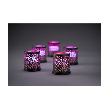 Acht cilindrische mini-kaarsenhouders uit het Multicolour LED-Set van Duni GmbH stralen door een uitgesneden patroon op een grijs oppervlak voor een donkere achtergrond.