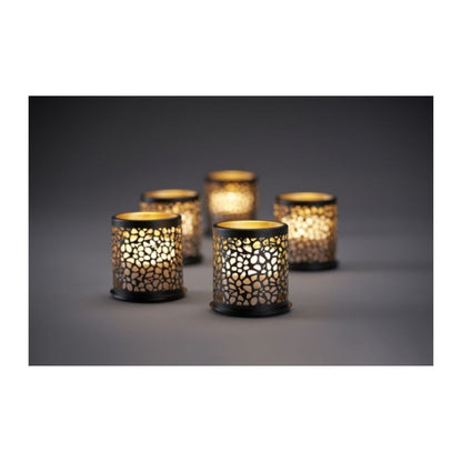 Acht kleurrijke Duni GmbH Multicolour LED Mini Kaarsen stralen door roosterachtige kaarsenhouders en werpen betoverende schaduwen op een eenvoudige oppervlakte voor creatieve verlichting in een schemerige sfeer.