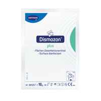 La photo montre un emballage du nettoyant désinfectant Hartmann Dismozon® plus de la société Paul Hartmann AG. Le design de l'emballage est principalement blanc, avec des touches de bleu et de vert, et comporte des consignes d'utilisation ainsi que des symboles. Chaque emballage contient 16 grammes de granulés oxygénés ; un carton contient 100 sachets.