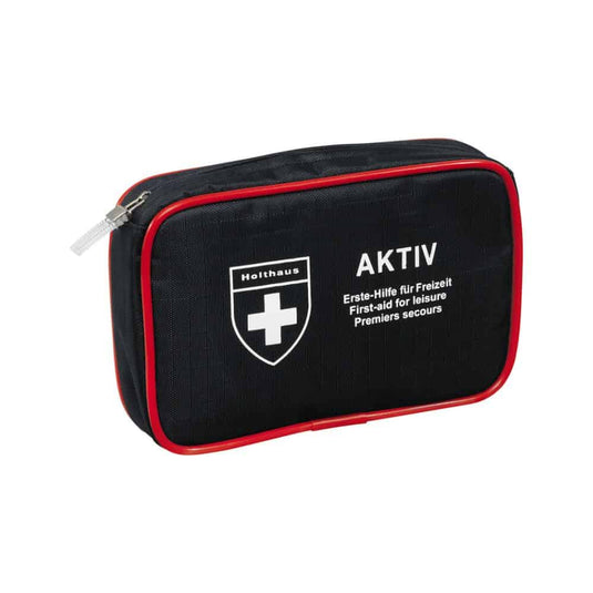 Une trousse de premiers secours compacte, noire, avec des bordures rouges et une fermeture à glissière, arborant un logo en forme de croix blanche ainsi que les inscriptions « Holthaus Medical AKTIV » et « Erste-Hilfe für Freizeit / First-aid for Leisure / Premiers secours » sur le devant. Idéale pour vos déplacements et à la maison.