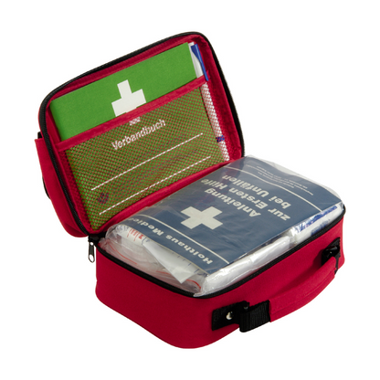 Une trousse de secours rouge compacte Holthaus Office plus, DIN 13 157 de Holthaus Medical GmbH & Co. KG, avec une poignée noire qui s'ouvre pour révéler le contenu. À l'intérieur se trouvent un manuel d'instructions vert et une trousse de secours bleue Holthaus, ornée d'une croix blanche et de texte allemand. L'équipement de premiers secours est organisé de manière claire dans des poches en filet et des compartiments, ce qui le rend idéal pour les environnements de bureau.