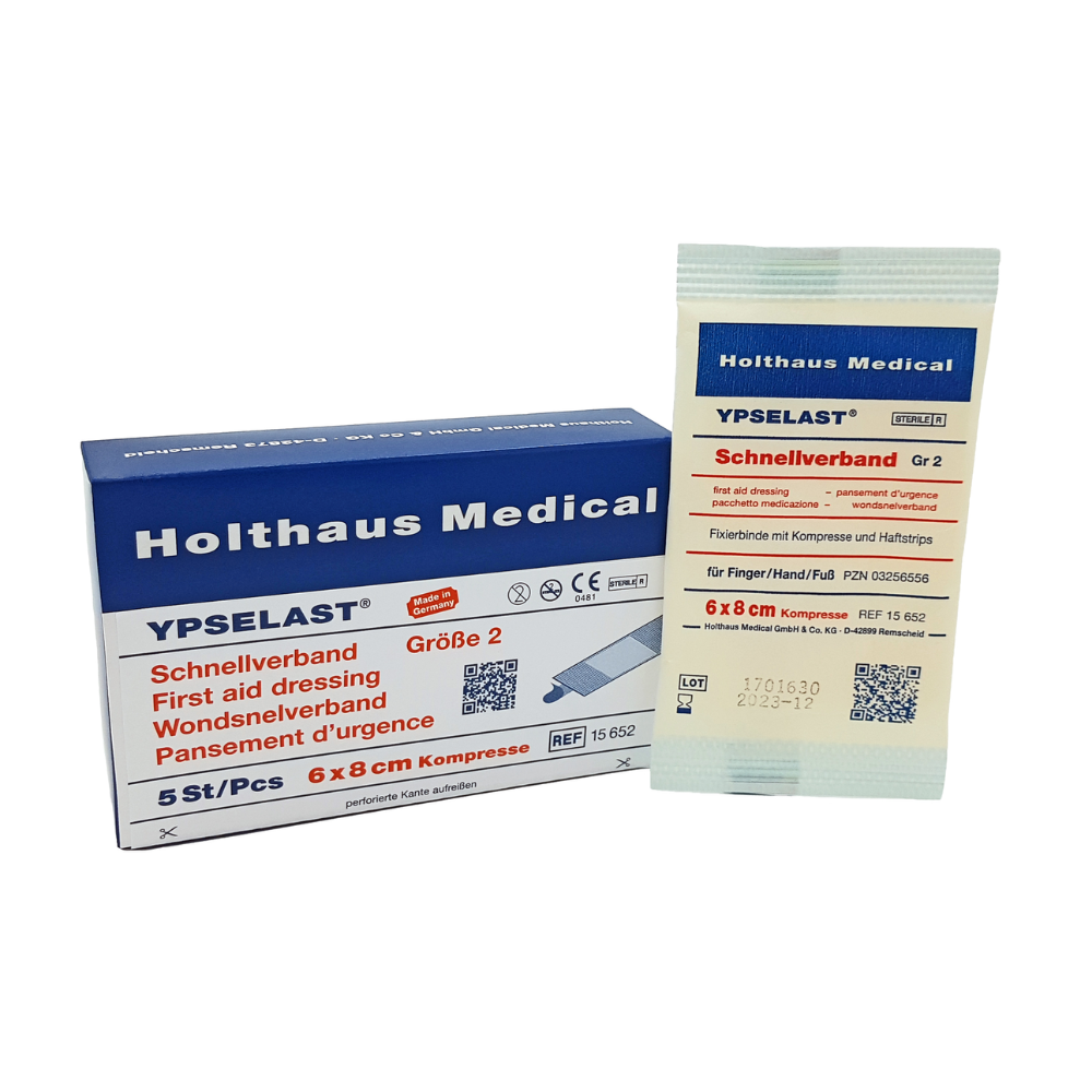 L'image montre un bandage rapide Holthaus Ypselast® de Holthaus Medical GmbH & Co. KG. À gauche, on voit une boîte bleu et blanche avec l'inscription « Bandage rapide Taille 2 » aux dimensions de 6x8 cm. À droite, un des bandages de fixation élastiques est illustré dans son emballage individuel blanc.
