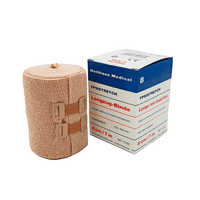 Op de verpakking staat een medisch elastisch verband afgebeeld. Op de doos staat „Holthaus Ypsistretch Langzug-Binde, krachtig” en de informatie is in het Duits. Het huidkleurige verband van Holthaus Medical GmbH & Co. KG biedt een effectieve compressie en wordt vastgemaakt met twee kunststof sluitingen.