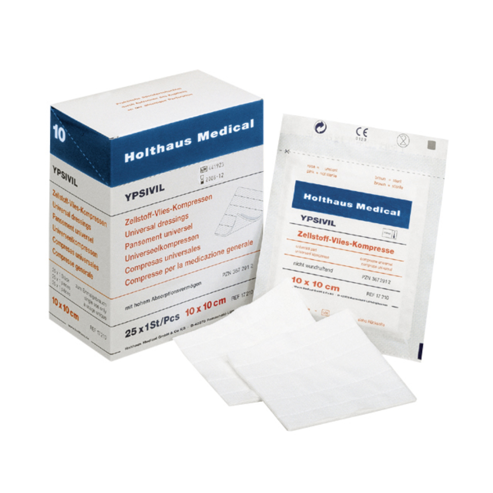 Een doos Holthaus Ypsivil cellulose-fleecekompres, 10 x 10 cm van Holthaus Medical GmbH & Co. KG staat naast een enkele, ongeopende verpakking van hetzelfde verband. Daarvoor liggen twee uitgevouwen vierkante verbanden, waarvan de grootte en materiaaleigenschappen duidelijk zichtbaar zijn.