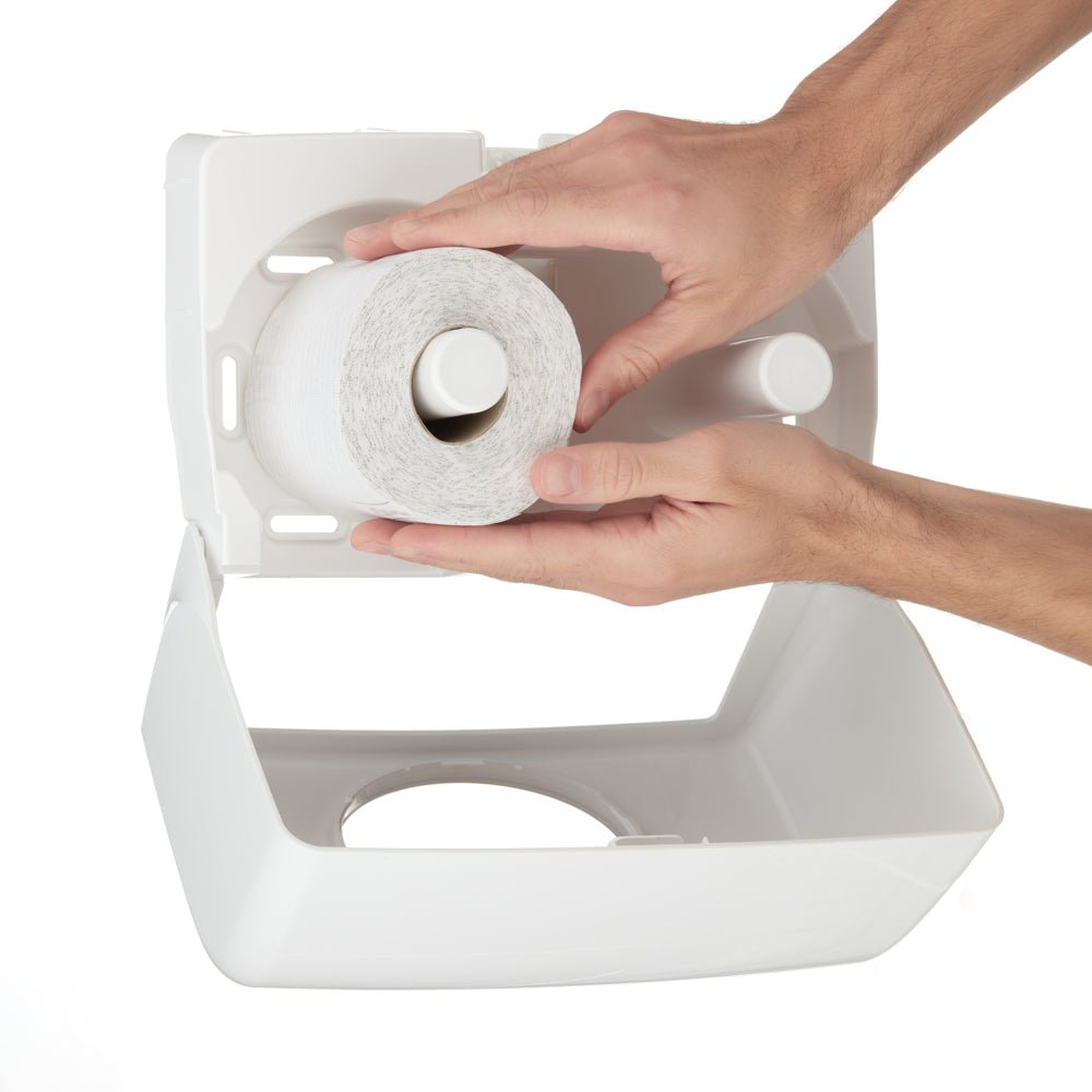 Une personne insère un nouveau rouleau de papier toilette Kleenex® de la société Kimberly-Clark GmbH d'un pack de 8 x 12 dans un distributeur en plastique blanc avec le couvercle ouvert.